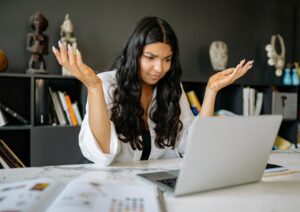 girl staring at computer with her hands up as if to say "what should I do"
