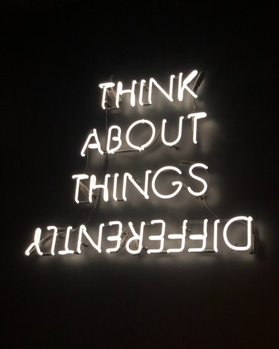 neon sign think about things differently with differently upside down