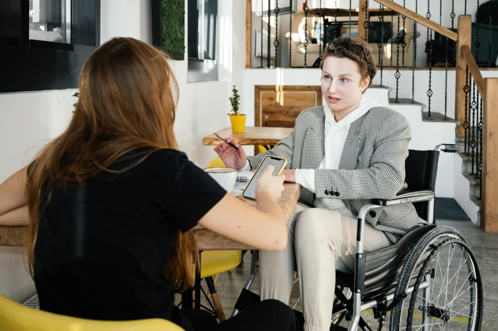 woman in wheelchair talking to another worman